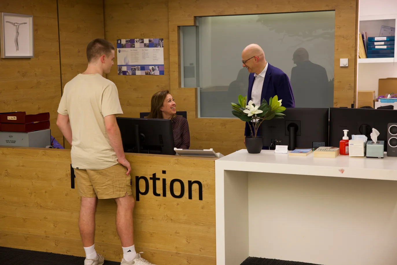 A patient being welcomed at a clinic reception desk.