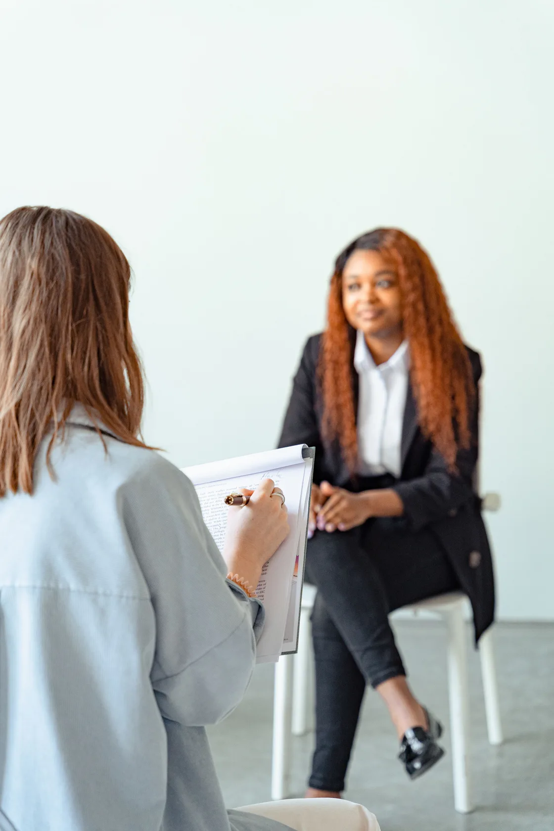 A clinician taking notes while talking with a smiling client