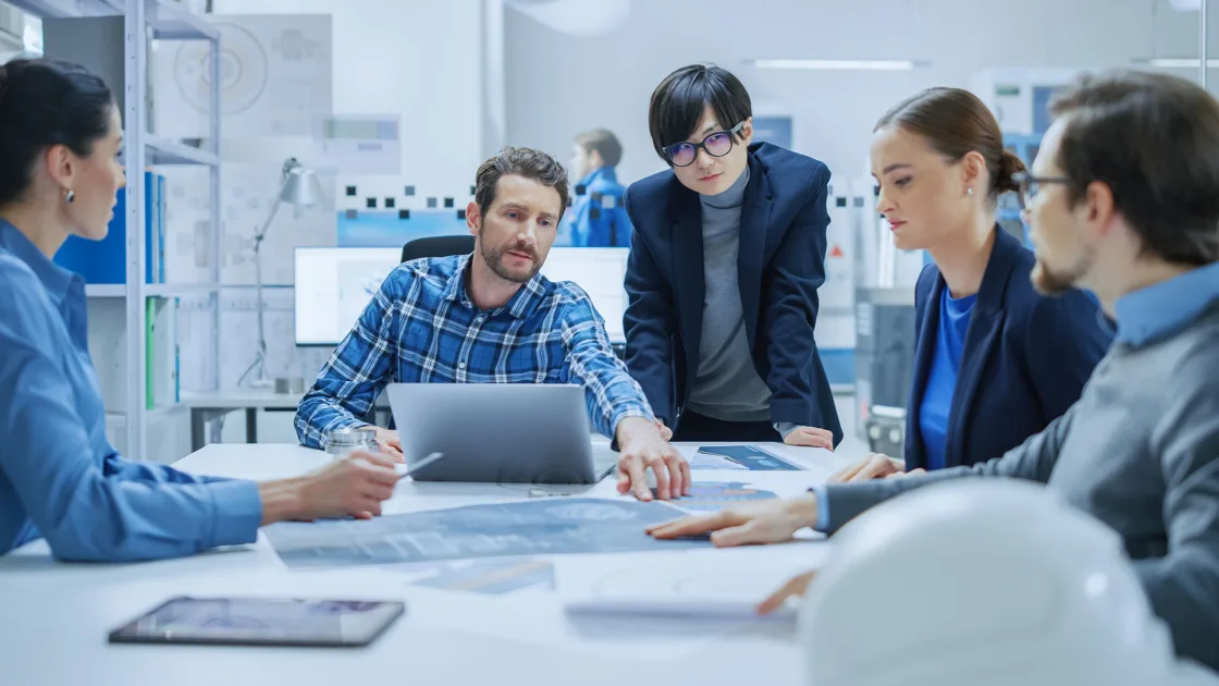 Colleagues collaborating around a laptop in a modern office